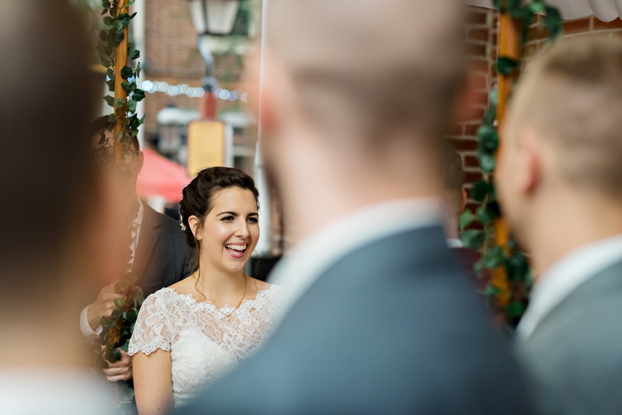 A view of the bride laughing through the row of groomsmen during the ceremony.